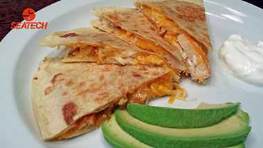 A photograph of a crab quesadilla with sliced avocado.