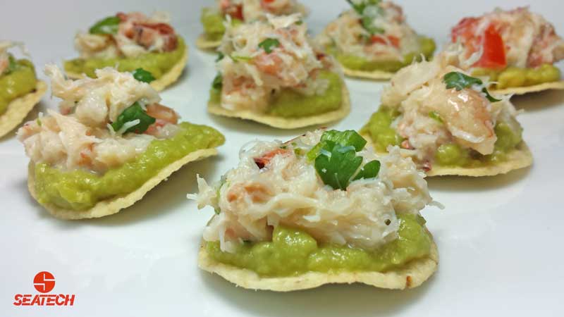 A photograph of mini crab tostada appetizers with crab meat, avocado, cilantro, onion, mayonnaise and lime juice.